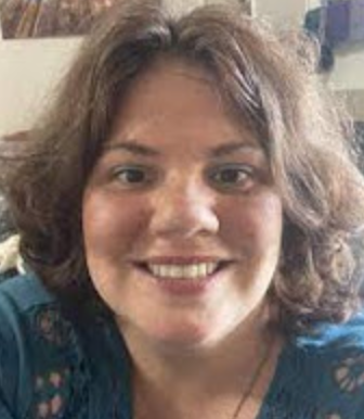Headshot photo of Meghan Schrader, a white woman with light brown curly shoulder length hair and blue clothing, smiling brightly.